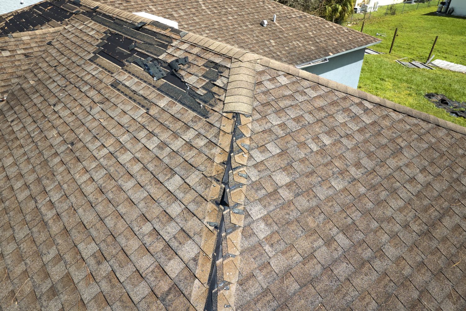 Damaged house roof with missing shingles after hurricane Ian in Florida. Consequences of natural disaster.