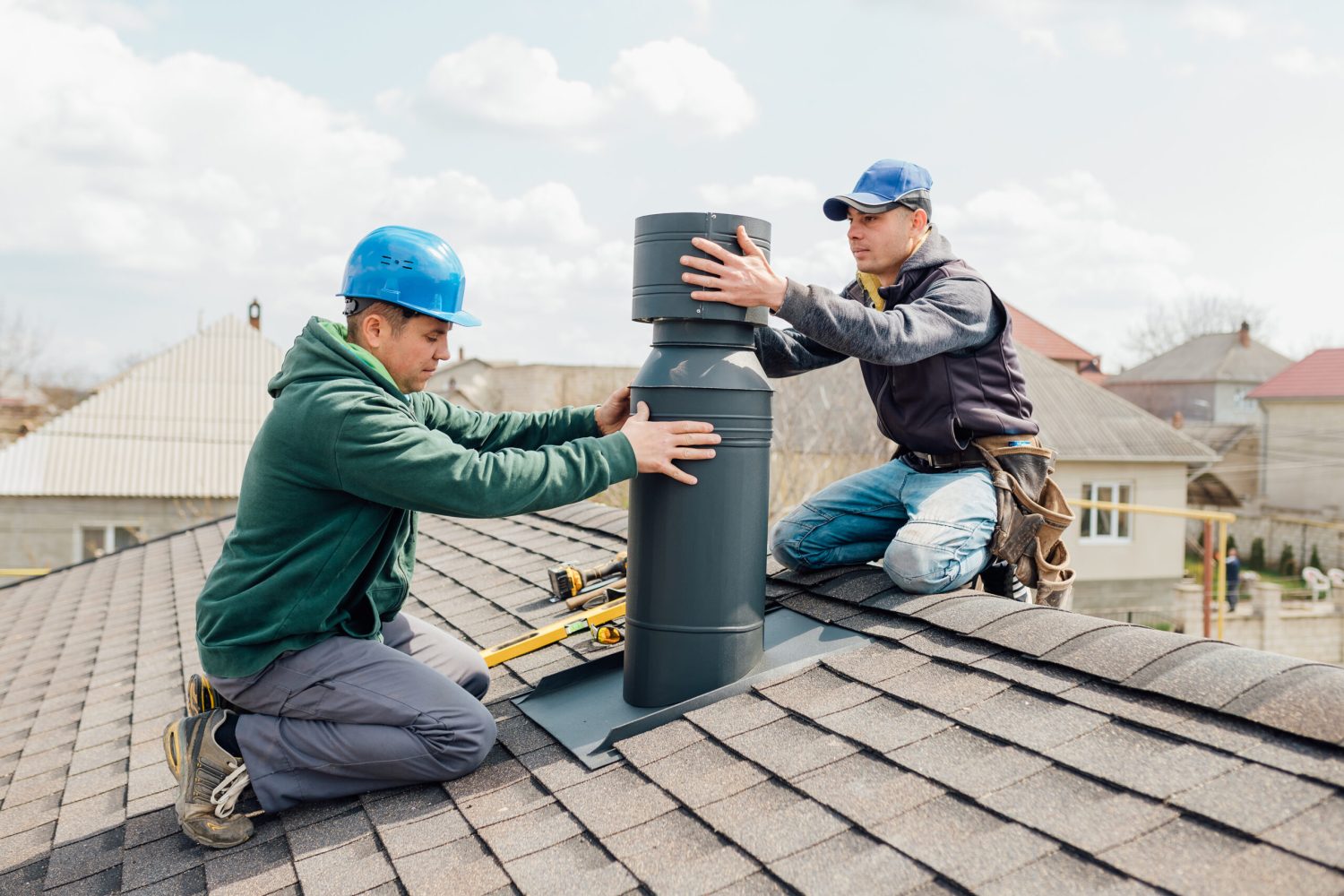 two Professional workmen's standing roof top and measuring chimney of new house under construction against blue background